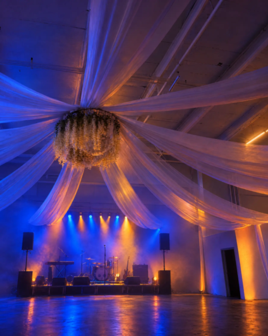 Concert stage illuminated in blue and amber beneath ceiling drapery at The Zion